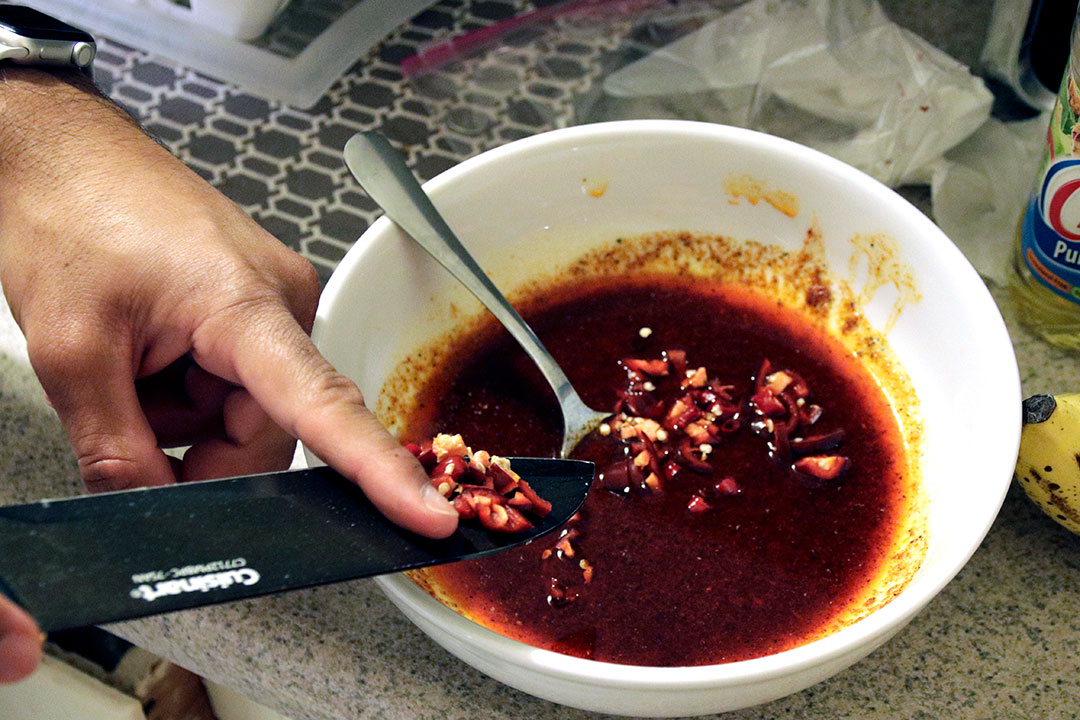 Adding fresh peppers to a sauce can improve both the flavor and the heat of the
sauce. Jaz Lail, Business Finance Senior, at his home kitchen in SLO 10/20/19